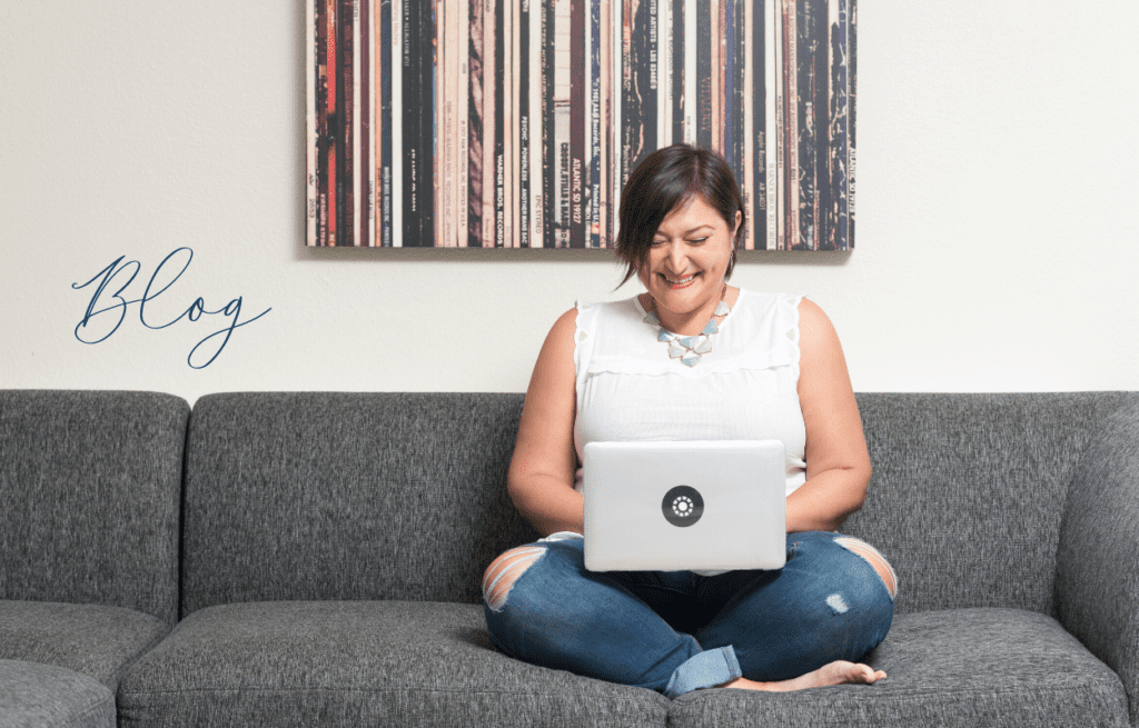 woman in white shirt on gray couch with laptop
